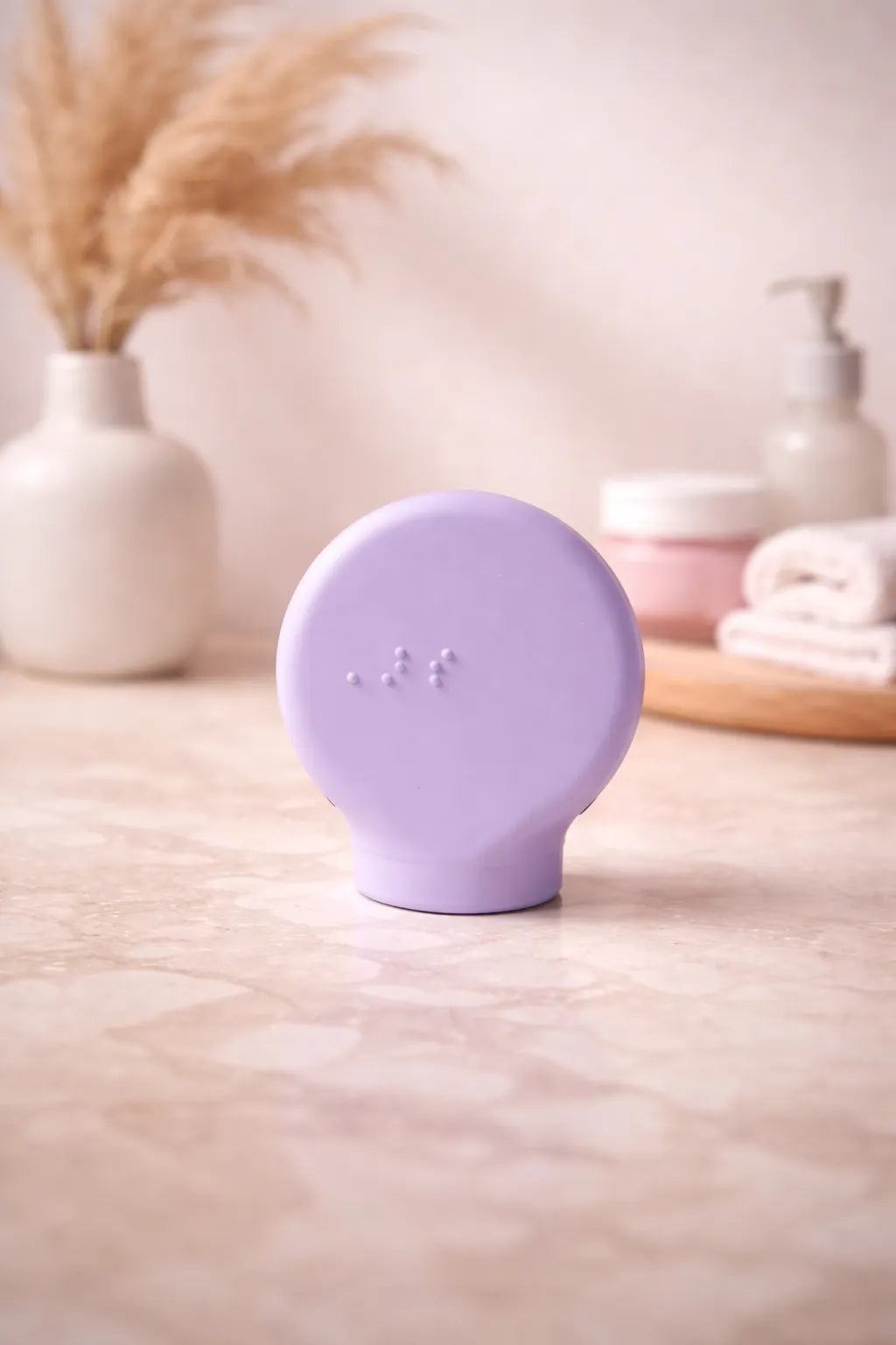 Margie a lilac paddle shape accessible makeup tool on a wooden surface with a blurred background