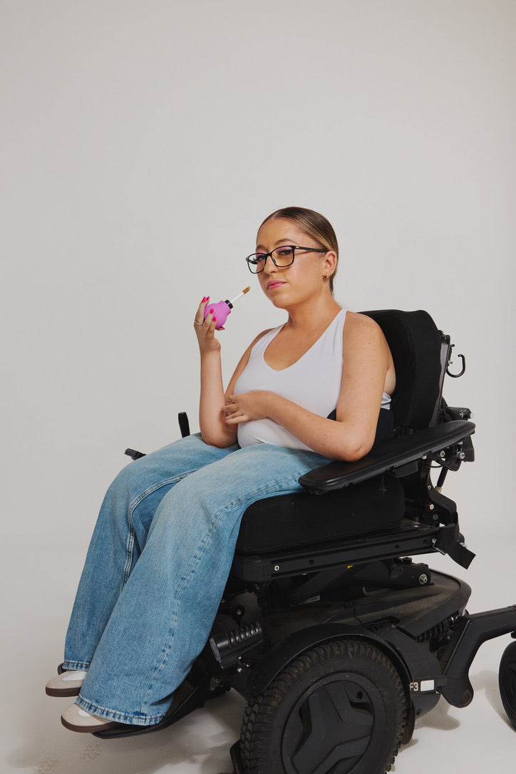 A woman using a wheelchair holding a pink ByStorm makeup grip