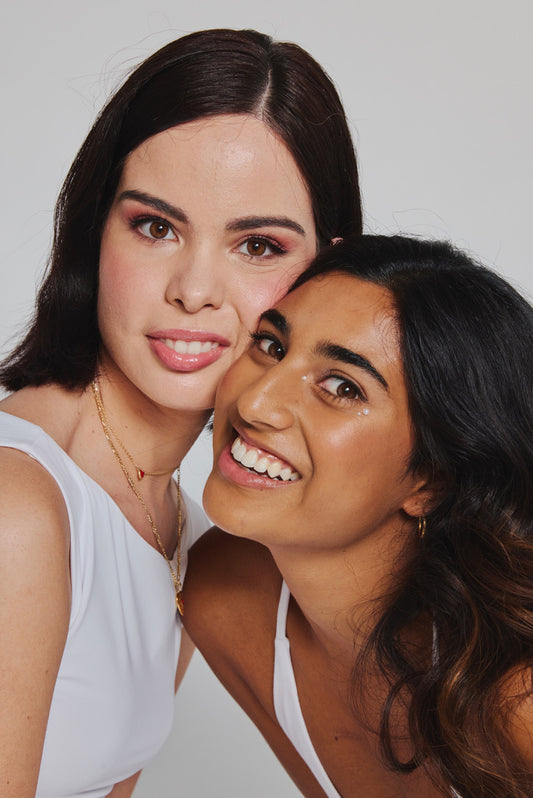 One woman helping another apply blush using a ByStorm makeup grip and brush