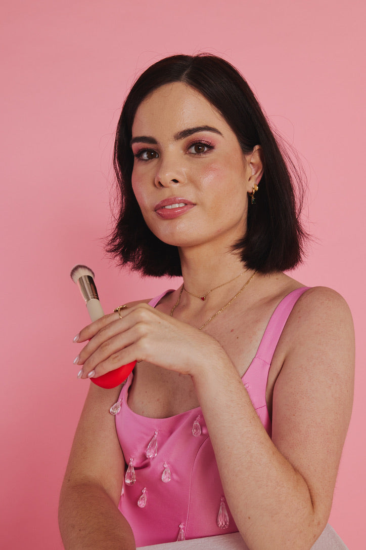 A woman holding a coral ByStorm makeup grip near her lips