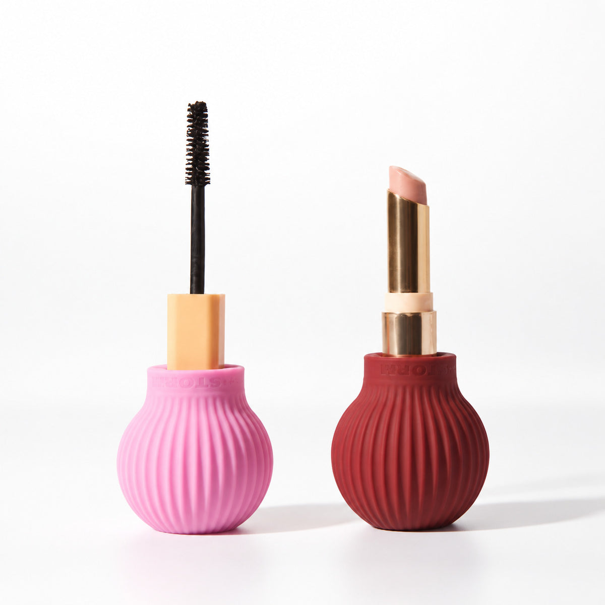 Pink ByStorm Betty grip holding a mascara beside a maroon Betty grip holding a lipstick, on a white background