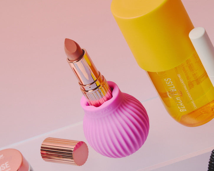 Betty, a pink ball-shaped adaptive grip holds a lipstick surrounded by other makeup items. 