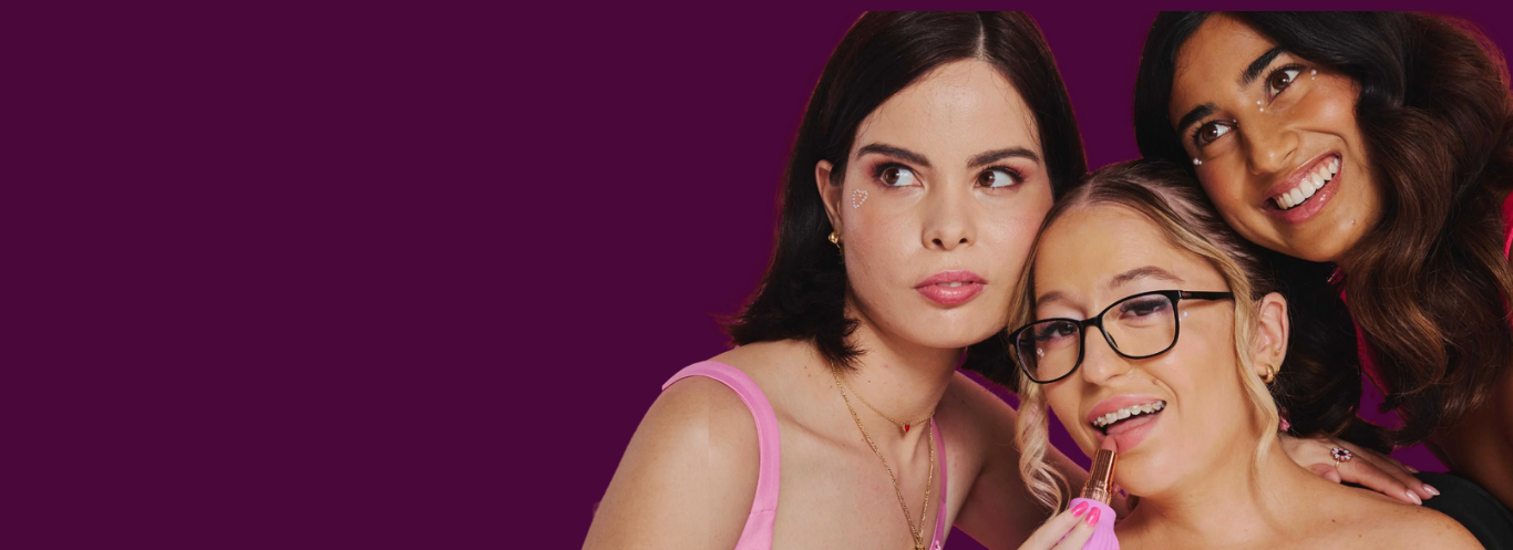 Group of three women wearing colorful pink, red and blue outfits hugging and smiling for a ByStorm Beauty campaign