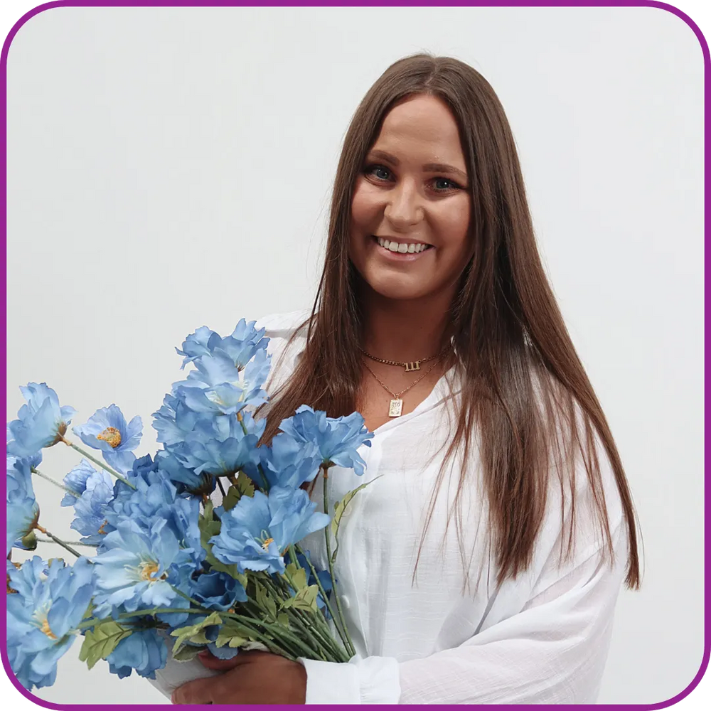 Woman holding a bouquet of blue flowers against a plain background