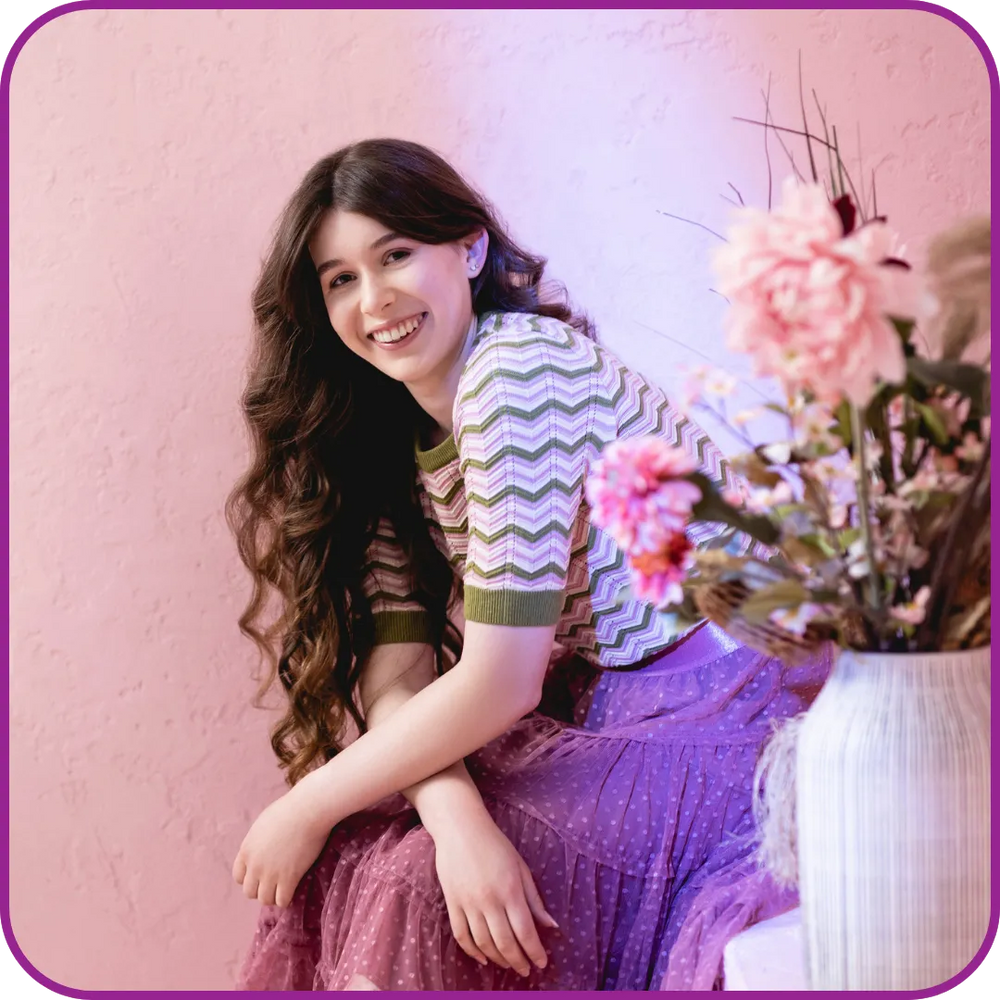 Woman sitting with flowers on a pink background