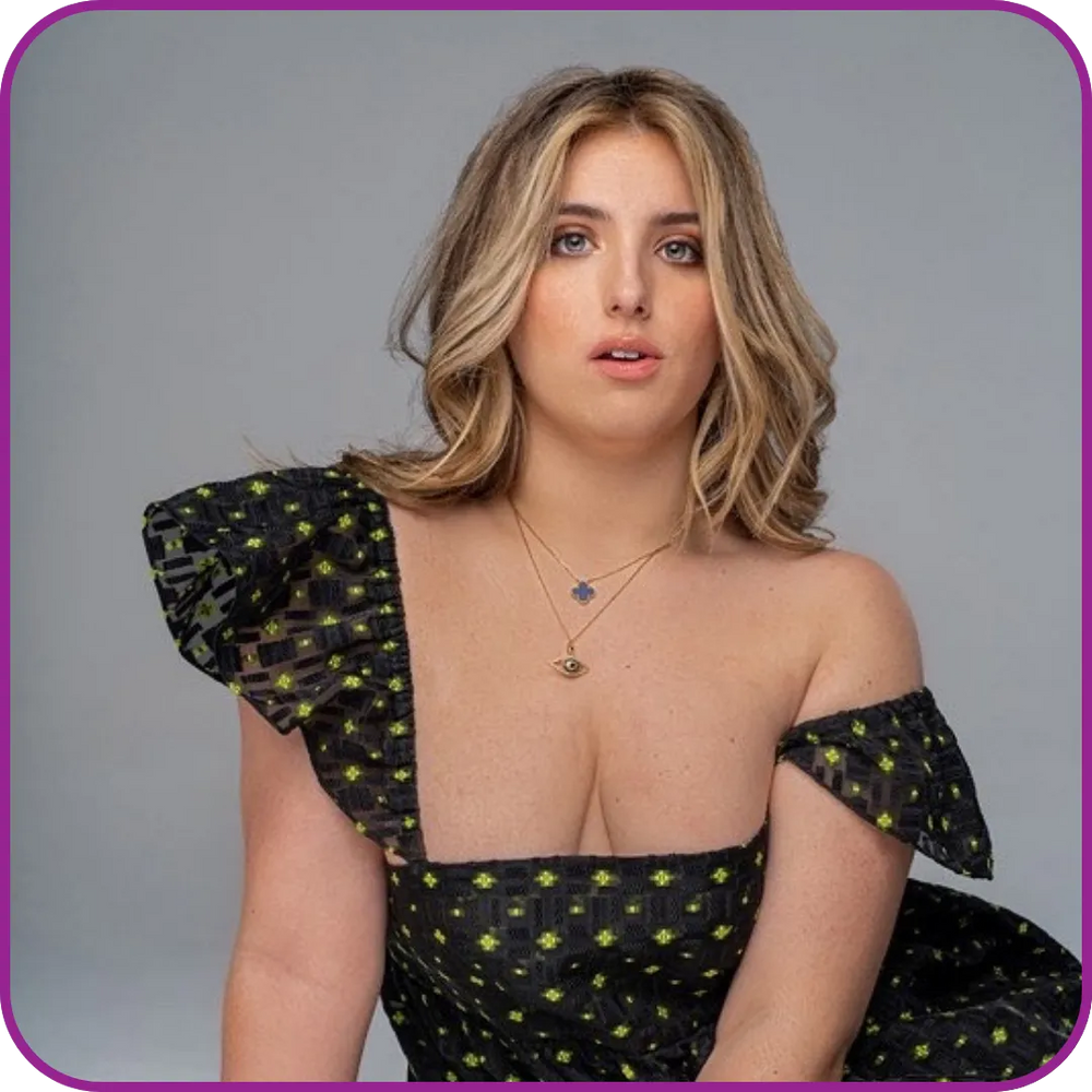 Woman wearing a black dress with sheer sleeves against a gray background