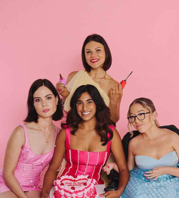 Group of women wearing pink, yellow and blue outfits smiling during a ByStorm Beauty campaign celebrating inclusivity. They are holding adaptive beauty tools. 