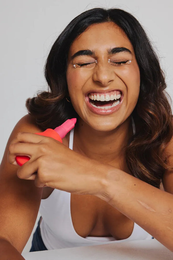 Woman confidently smiling while using a ByStorm accessible grip tool attached to her lipstick