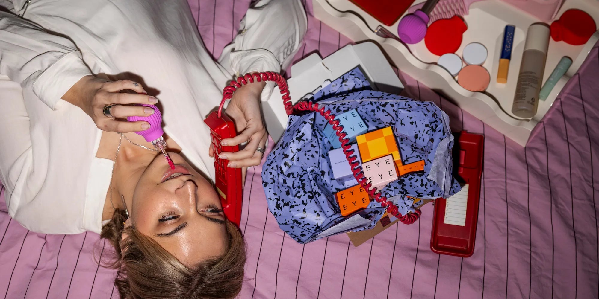 Woman holding Betty, a pink ball-shaped adaptive makeup grip by ByStorm with lipgloss attached for easier application