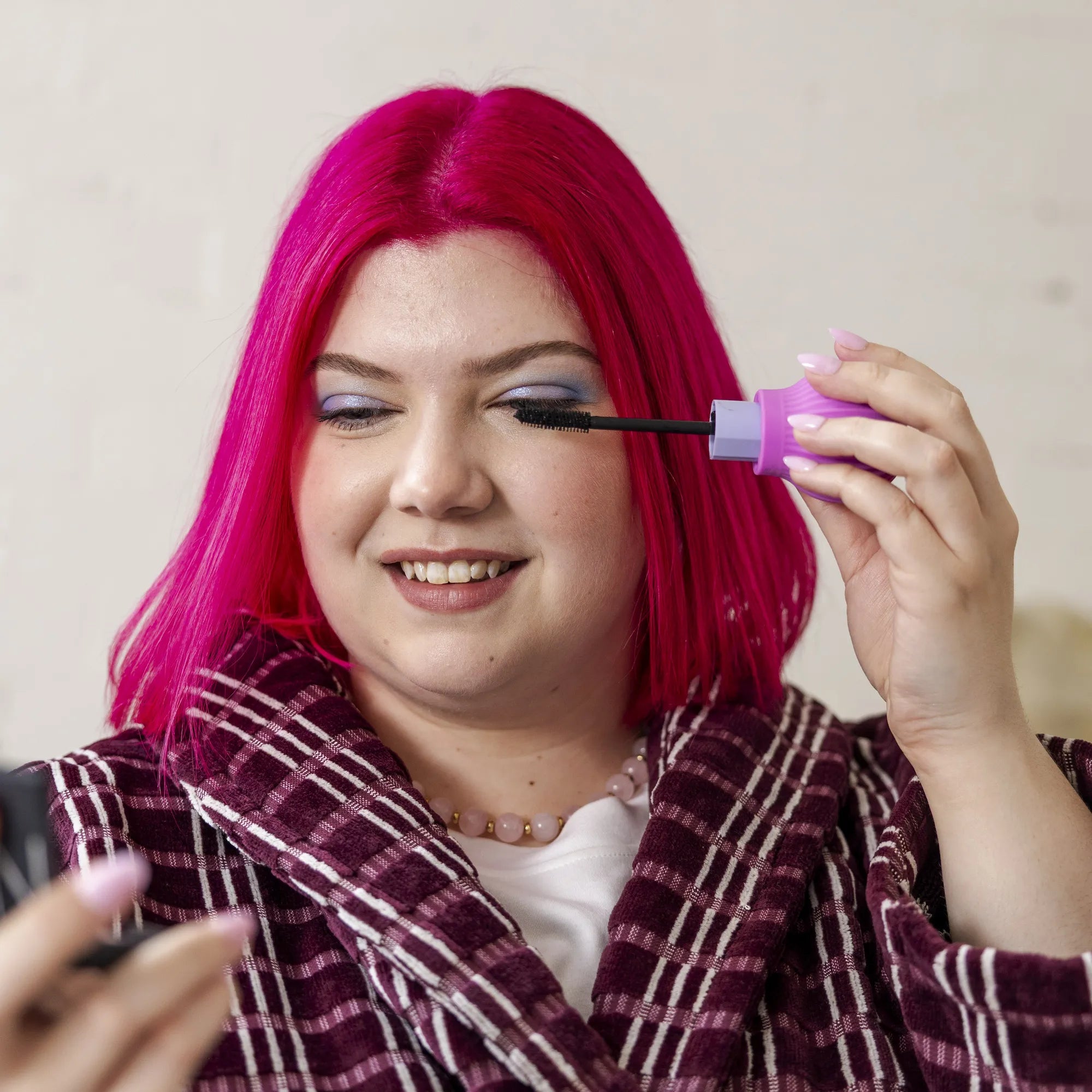 Woman smiling while applying mascara using a ByStorm adaptive makeup grip tool during her morning routine