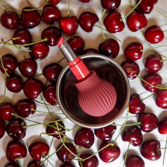 Betty, a mauve ball-shaped accessible makeup tool by ByStorm, holding a lipstick on a white background
