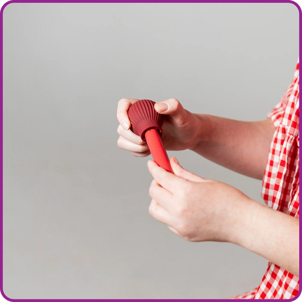 Person holding Betty, a mauve ball-shaped adaptive makeup grip by ByStorm with lipstick attached for easier opening.