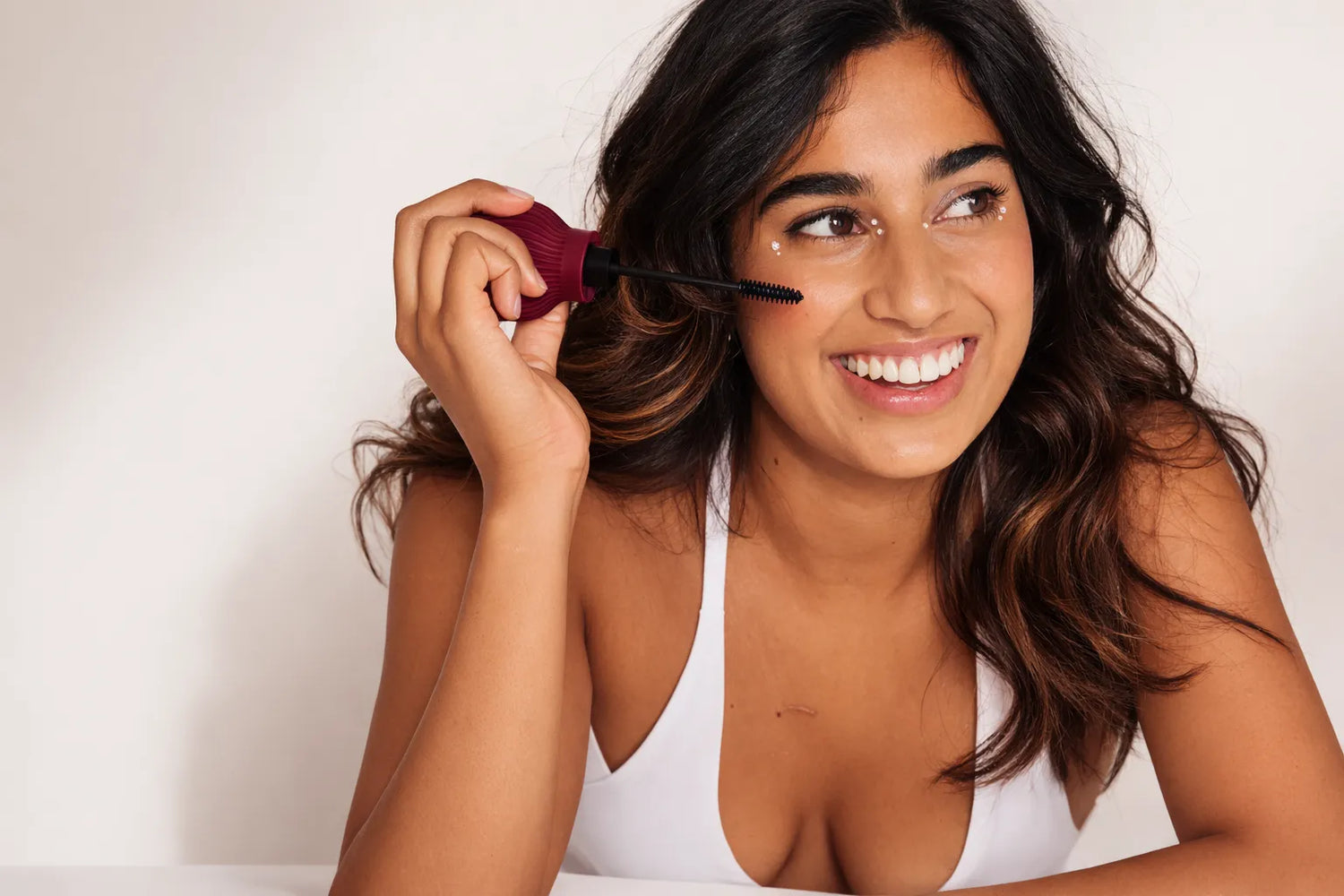 Woman applying mascara attached to ByStorm accessible grip tool with a white background