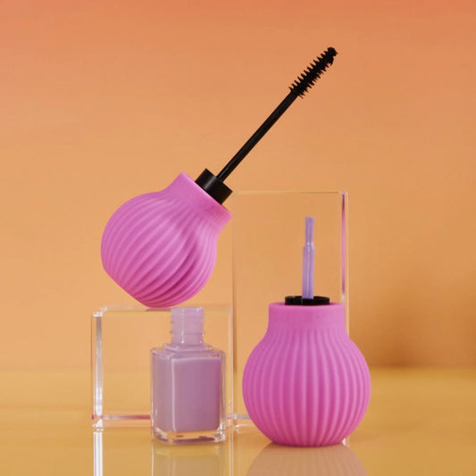 Two ByStorm accessible makeup grip tool  holding a mascara wand and nail polish brush, displayed on clear acrylic blocks