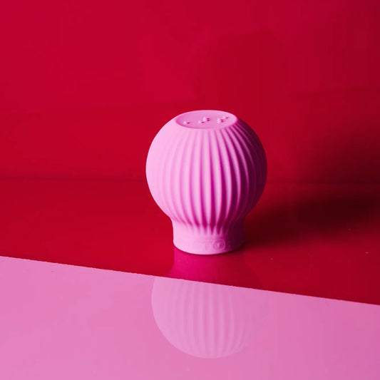 Betty, a pink ball-shaped accessible makeup grip tool by ByStorm on a red and pink background