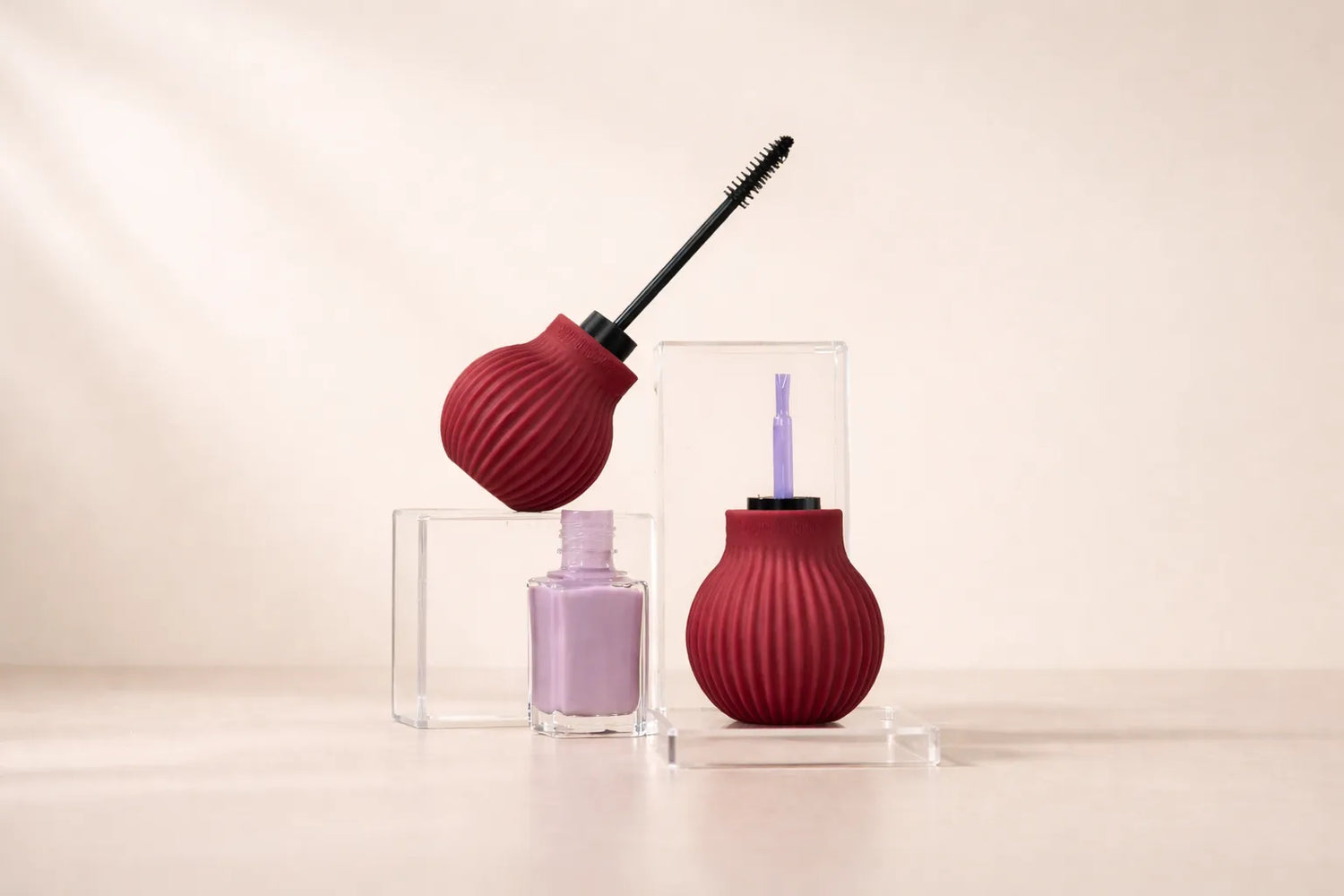 ByStorm accssible grip tool attached to a mascara wand and a nail polish on a beige background