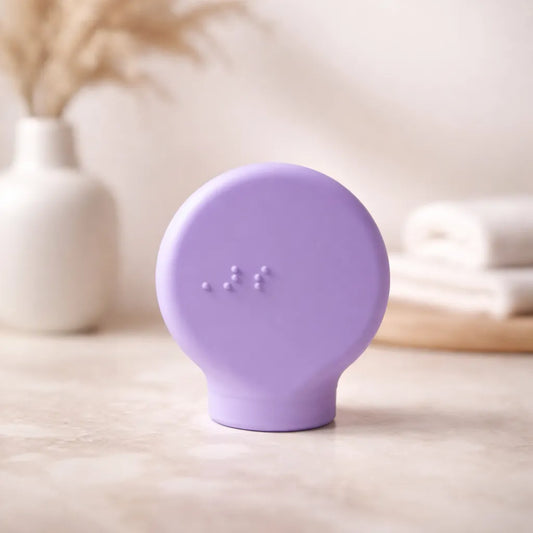Margie a lilac paddle shape accessible makeup tool on a light wooden surface with a blurred background
