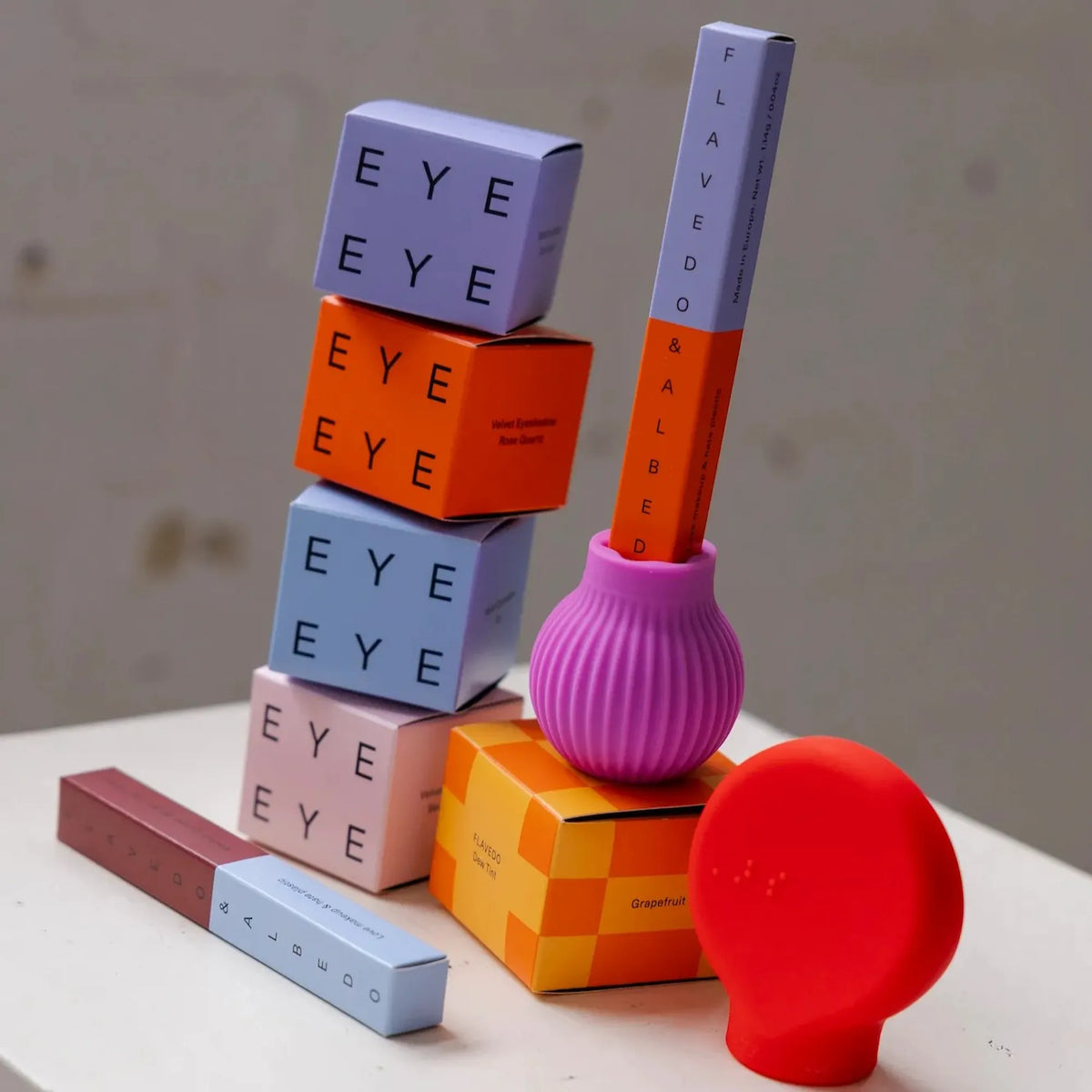 Colourful cosmetics and ByStorm adaptive makeup grip tools with lipsticks and brushes on a white surface