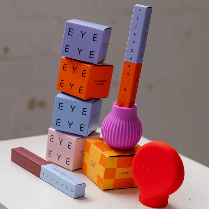 Colourful cosmetics and ByStorm adaptive makeup grip tools with lipsticks and brushes on a white surface